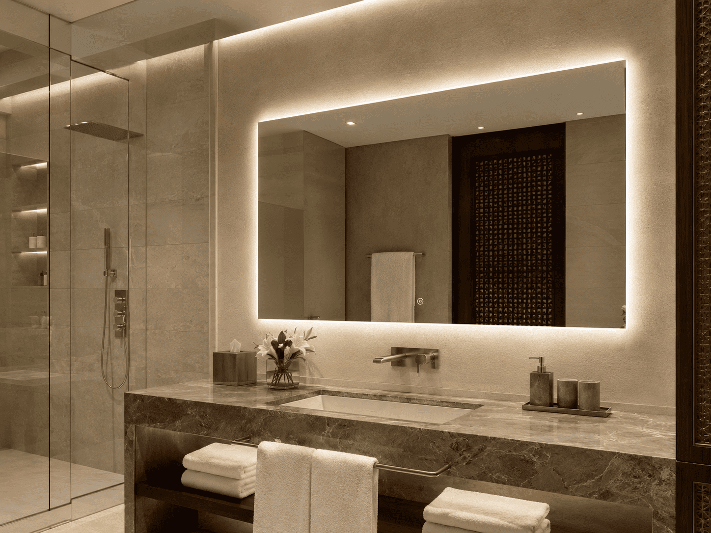 Warm-lit rectangular LED bathroom mirror installed above a stone vanity in a luxury Saudi hotel bathroom